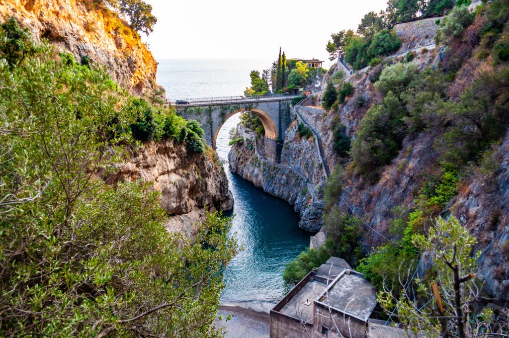 View on Fiordo di Furore arc bridge built between high rocky cliffs above the Tyrrhenian sea bay in Campania region. Unique cove under the cliffs, natural gorge, canyon or fiord