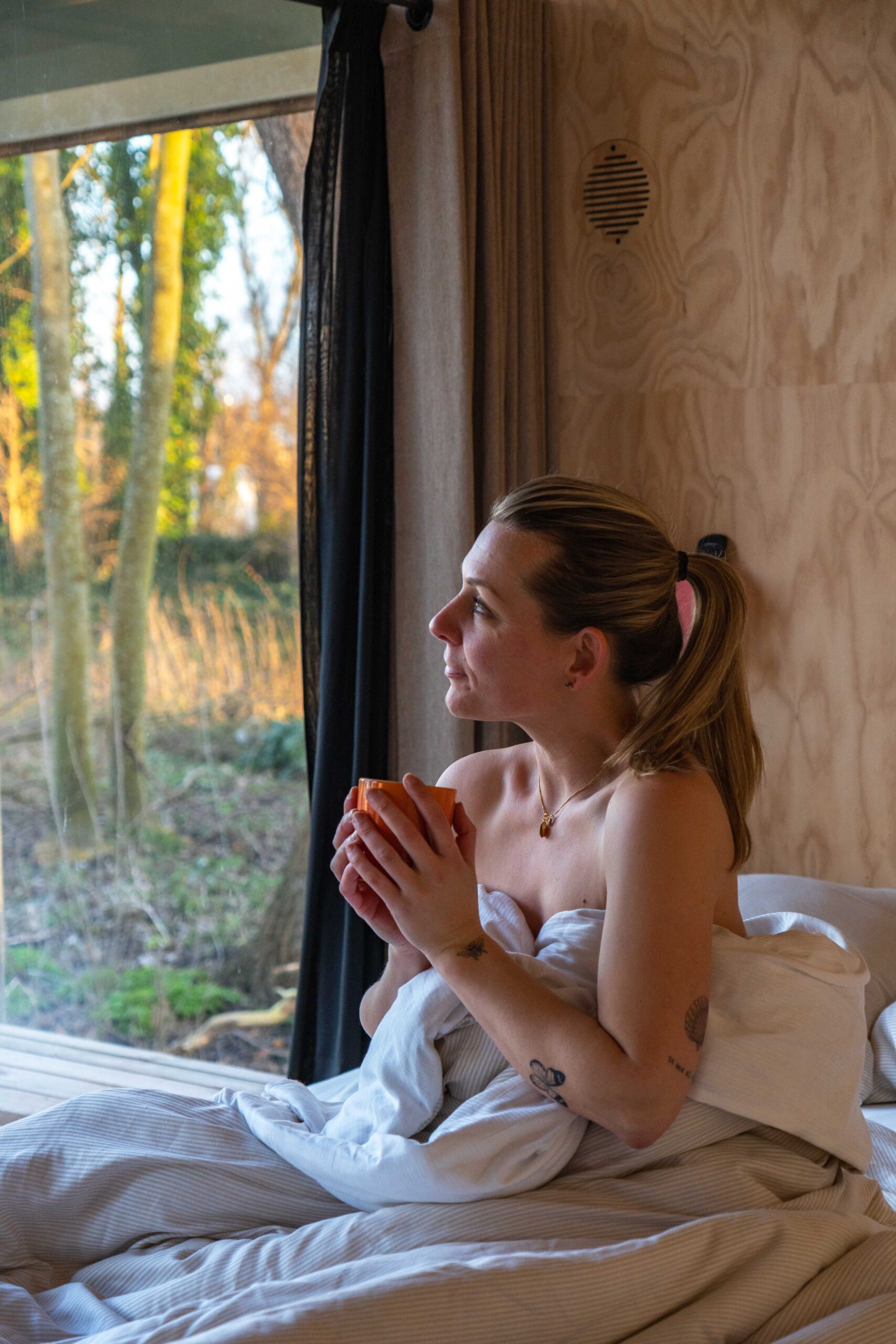 vrouw aan het genieten van een koffie in bed in de cabin