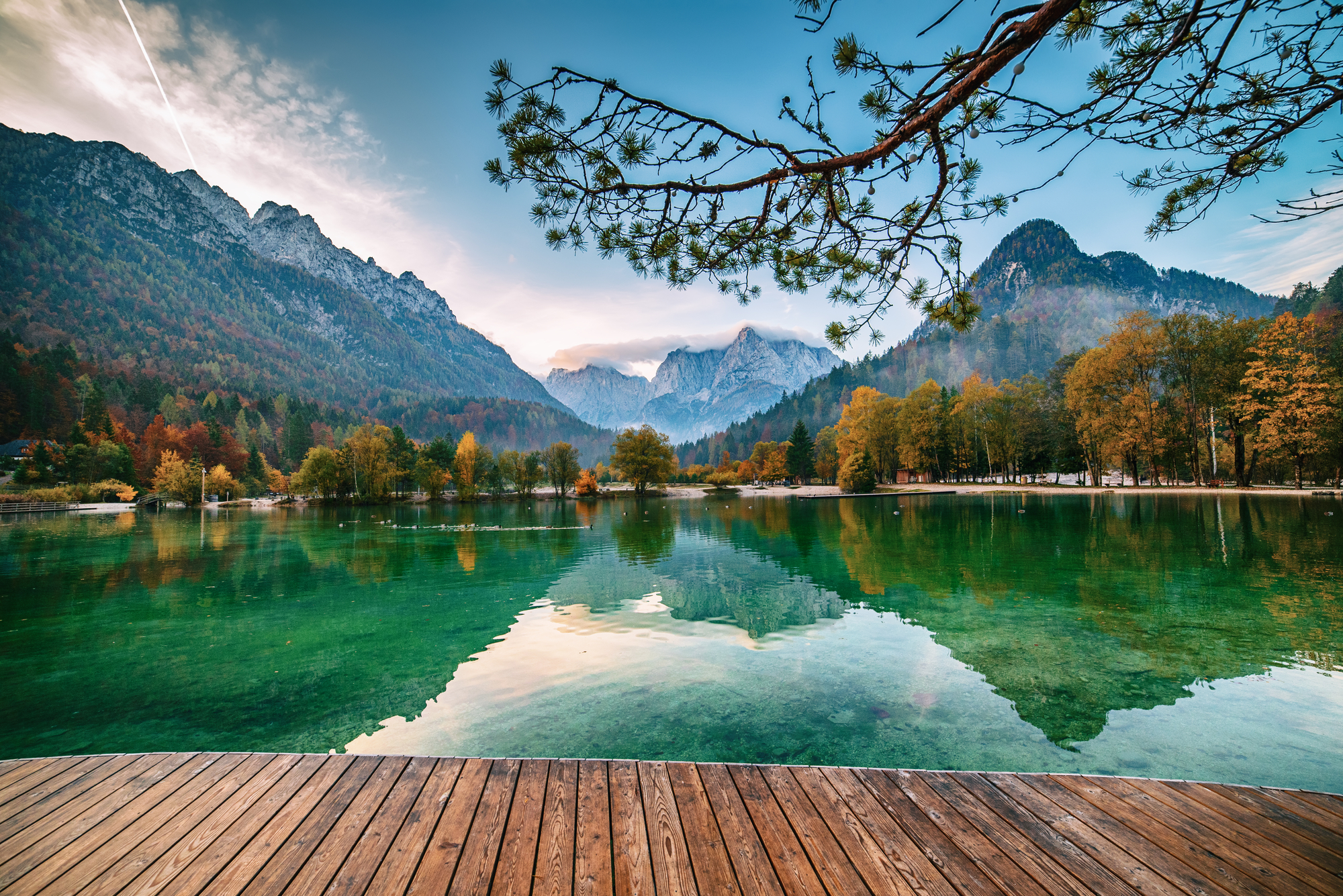 Jasna lake with beautiful reflections of the mountains and wooden pier. Triglav National Park, Slovenia